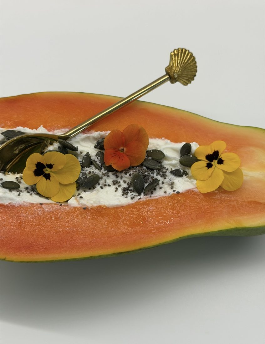 Papaya half with yogurt, seeds and edible flowers